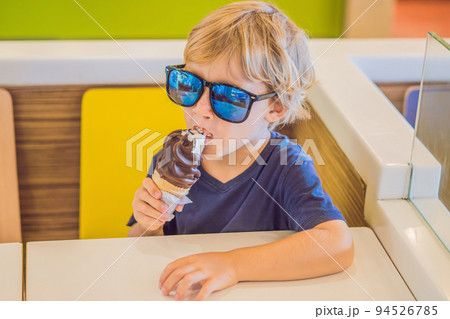 Little boy eating ice cream at an cafe Little boy eating ice cream at an cafe 94526785