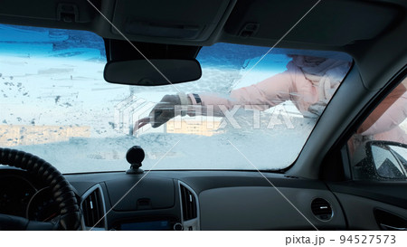 Young Woman Cleaning Frozen Windshield with Ice Scraper, Winter Season Young Woman Cleaning Frozen Windshield with Ice Scraper, Winter Season 94527573