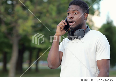 Black man talks on phone with friend discussing holiday 94528235