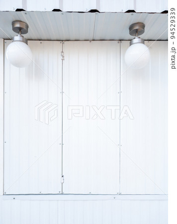The white couple's electric lantern is hanging near the white metal window. 94529339