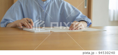 家で電卓を使う女性。家計、支払い、支払額、予算、ローン、計算など 家で電卓を使う女性。家計、支払い、支払額、予算、ローン、計算など 94530240