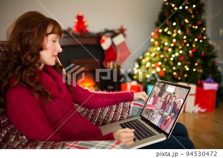 Caucasian woman on christmas laptop video call with diverse group of friends 94530472