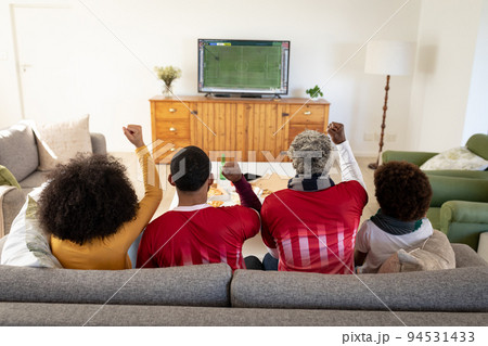 African american family sitting on the couch and watching football match on laptop 94531433