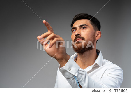 Young Arab businessman working with virtual screen over grey background. Young Arab businessman working with virtual screen over grey background. 94532602