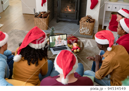 Biracial friends in santa hats on laptop christmas video call with smiling senior woman Biracial friends in santa hats on laptop christmas video call with smiling senior woman 94534549