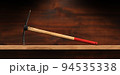 Pickaxe with Wooden Handle on a Wooden Workbench 94535338
