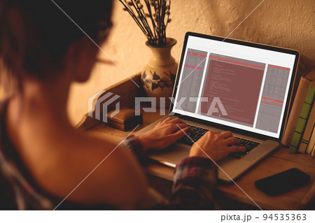 Back view of caucasian female programmer sitting at desk, using laptop with coding on screen 94535363