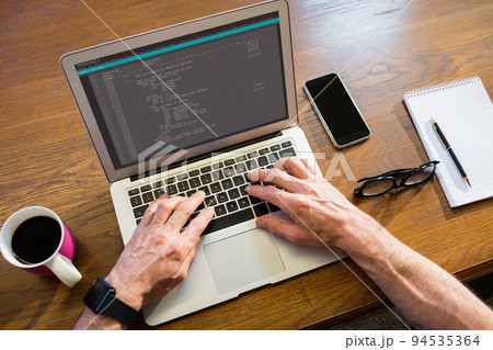 Hands of caucasian male programmer sitting at desk, using laptop with coding on screen 94535364