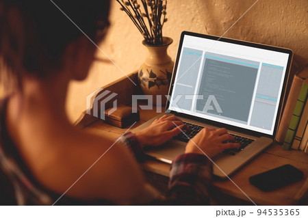 Back view of caucasian female programmer sitting at desk, using laptop with coding on screen 94535365
