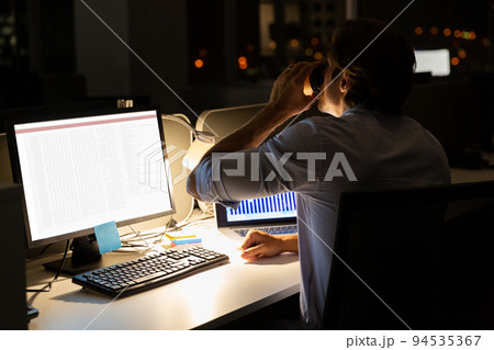 Caucasian male programmer drinking coffee, sitting at desk and using computer with coding on screen 94535367