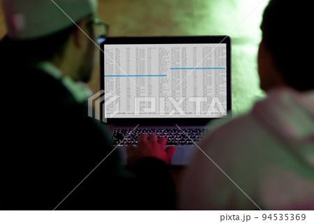 Back view of two diverse male colleagues using laptop with coding on screen 94535369