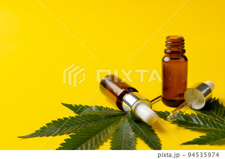 Image of bottle of cbd oil and marihuana leaves on yellow surface Image of bottle of cbd oil and marihuana leaves on yellow surface 94535974
