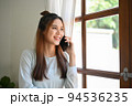 Attractive Asian woman looking out the window while on the phone with her boyfriend 94536235