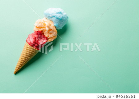 Horizontal image of three coloured flavours of ice cream in cone, on blue background with copy space 94536561