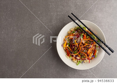 Overhead view of asian wok stir fry and chopsticks with copy space on grey background Overhead view of asian wok stir fry and chopsticks with copy space on grey background 94536633