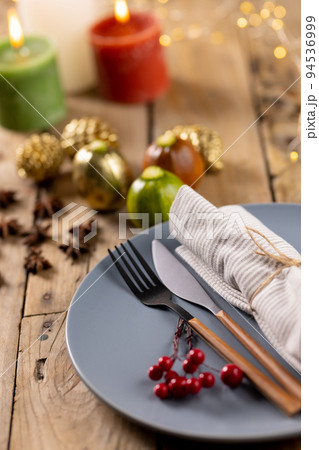 Overhead view of plate and cutlery with autumn decoration and candles on wooden background 94536999