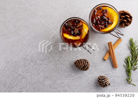 Image of two cups of tea with spices and lemon and christmas decorations with copy space on grey 94539220