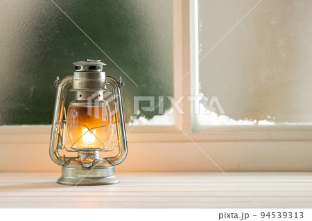 Vintage christmas shining oil lantern over frozen and snowy window 94539313