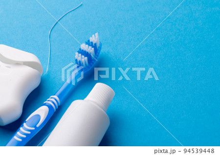 Image of toothbrush, toothpaste and dental string on blue surface Image of toothbrush, toothpaste and dental string on blue surface 94539448
