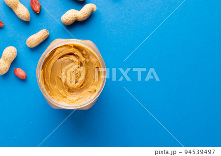 Image of peanut butter jar and nuts on blue background 94539497