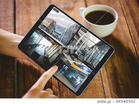 Hands of caucasian woman holding tablet with views of offices from security cameras on screen Hands of caucasian woman holding tablet with views of offices from security cameras on screen 94540502