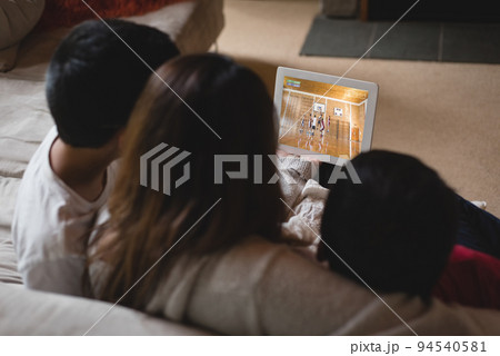 Back view of latin mother and children at home watching basketball game on laptop Back view of latin mother and children at home watching basketball game on laptop 94540581