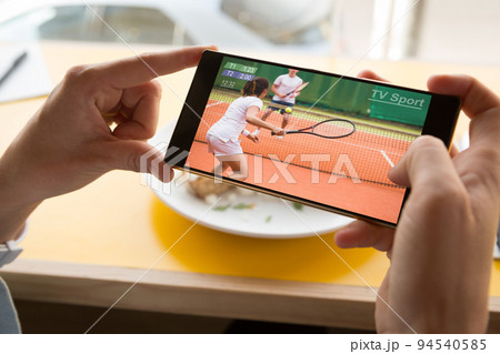 Hands of caucasian man at restaurant tennis match on smartphone 94540585