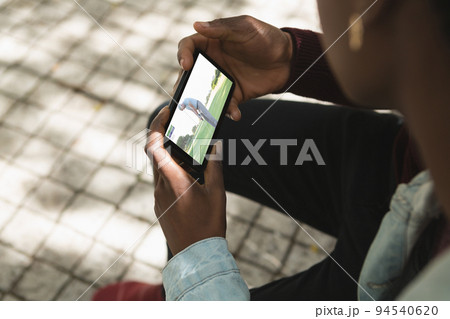 African american man in park watching golf on smartphone African american man in park watching golf on smartphone 94540620