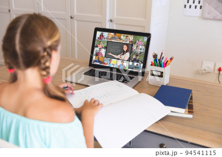 Caucasian girl using laptop for video call, with diverse elementary school pupils on screen 94541115