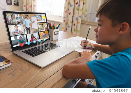Smiling caucasian boy using laptop for video call, with diverse elementary school pupils on screen Smiling caucasian boy using laptop for video call, with diverse elementary school pupils on screen 94541347