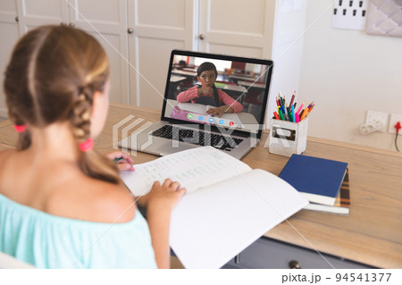 Caucasian girl using laptop for video call, with elementary school pupil on screen 94541377