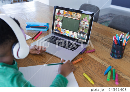 African american boy using laptop for video call, with diverse elementary school pupils on screen 94541403