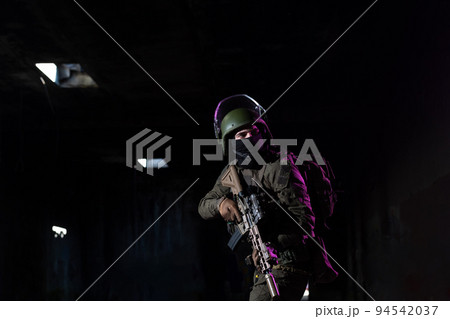 Army soldier in Combat Uniforms with an assault rifle and combat helmet night mission dark background. Blue and purple gel light effect. Army soldier in Combat Uniforms with an assault rifle and combat helmet night mission dark background. Blue and purple gel light effect. 94542037