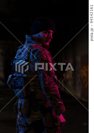 Army soldier in Combat Uniforms with an assault rifle and combat helmet night mission dark background. Blue and purple gel light effect. Army soldier in Combat Uniforms with an assault rifle and combat helmet night mission dark background. Blue and purple gel light effect. 94542161