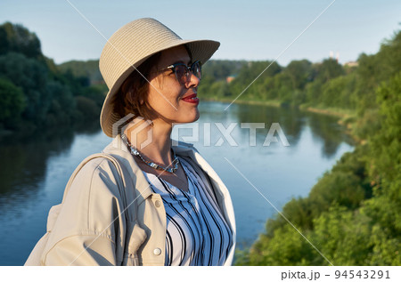 Portrait of travelling woman in hat against the backdrop of a river landscape Portrait of travelling woman in hat against the backdrop of a river landscape 94543291