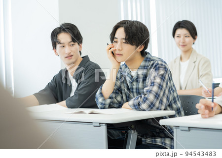 授業中ぼーっとする男子大学生とそれを横で睨む大学生 94543483