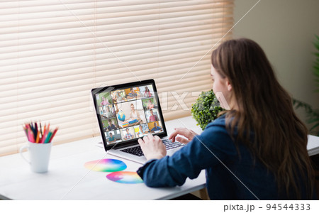 Caucasian girl using laptop for video call, with smiling diverse elementary school pupils on screen 94544333