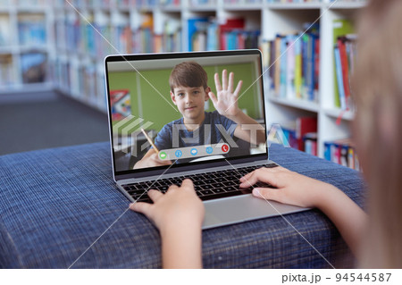 Caucasian girl using laptop for video call, with waving elementary school pupil on screen Caucasian girl using laptop for video call, with waving elementary school pupil on screen 94544587