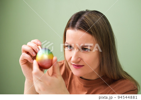 A young beautiful woman in a brown t-shirt paints Easter eggs in different colors. Preparing Easter Eve at home. Green wall. A young beautiful woman in a brown t-shirt paints Easter eggs in different colors. Preparing Easter Eve at home. Green wall. 94544881