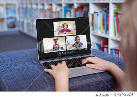 Caucasian girl using laptop for video call, with smiling diverse elementary school pupils on screen Caucasian girl using laptop for video call, with smiling diverse elementary school pupils on screen 94545074