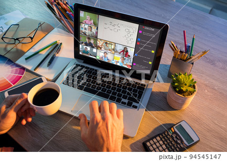 Hands of man using laptop for video call, with smiling diverse elementary school pupils on screen 94545147