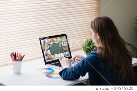 Caucasian girl using laptop for video call, with smiling diverse elementary school pupils on screen 94545220