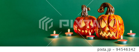 Halloween composition with diy ceramic pumpkins jack lantern and candles on pine green background Halloween composition with diy ceramic pumpkins jack lantern and candles on pine green background 94546342