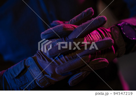 Photo of a fully equipped soldier in black armor tactical vest and gloves standing on black background closeup front view. Photo of a fully equipped soldier in black armor tactical vest and gloves standing on black background closeup front view. 94547219