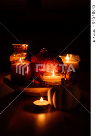 Autumn thanksgiving home decor with pumpkins and burning candles on table. Dark moody banner decorations with pumpkin and candles 94548045
