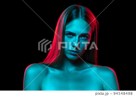 Young adorable woman with naked shoulders and well-kept skin in red neon light on dark background. Art, creativity, fashion, style Young adorable woman with naked shoulders and well-kept skin in red neon light on dark background. Art, creativity, fashion, style 94548498
