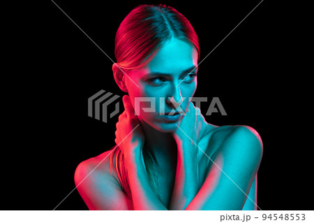 Young adorable woman with naked shoulders and well-kept skin in red neon light on dark background. Art, creativity, fashion, style 94548553