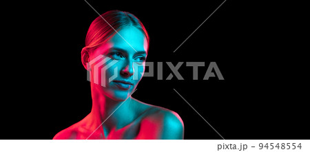Closeup portrait of young pretty woman with naked shoulders in red neon light on dark background. Art, creativity, fashion, style 94548554