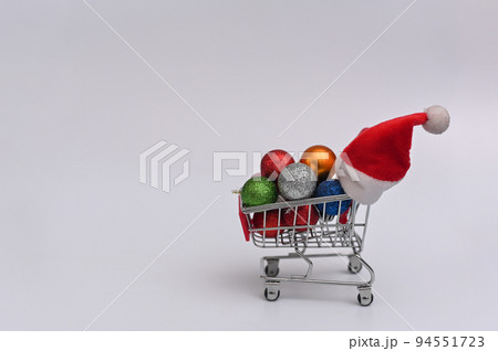 Shopping basket with Christmas balls and Santa hat..The concept of shopping for Christmas and New Year. copy space Shopping basket with Christmas balls and Santa hat..The concept of shopping for Christmas and New Year. copy space 94551723