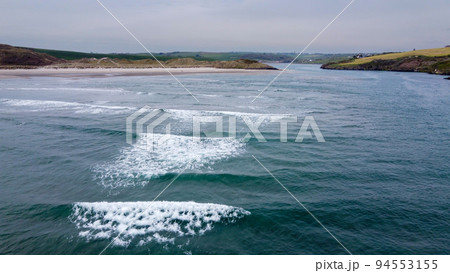 View of Inchydoney beach from the sea at high tide. Beautiful sea waves, surf. Aerial photo. View of Inchydoney beach from the sea at high tide. Beautiful sea waves, surf. Aerial photo. 94553155
